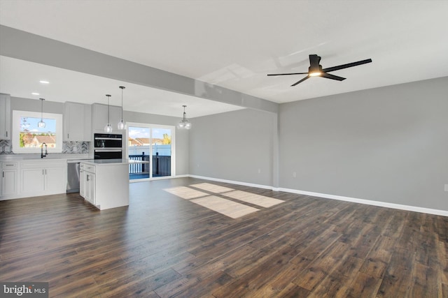 unfurnished living room featuring dark wood-type flooring, sink, and ceiling fan