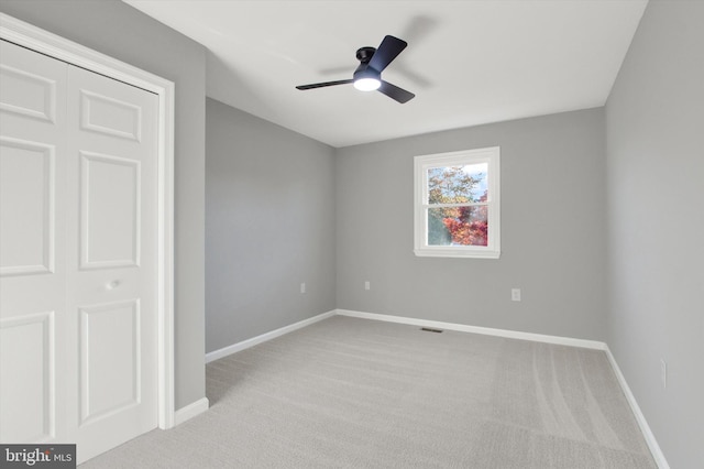 unfurnished bedroom with ceiling fan, a closet, and light colored carpet