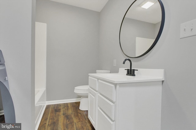 bathroom featuring toilet, vanity, wood-type flooring, and a tub