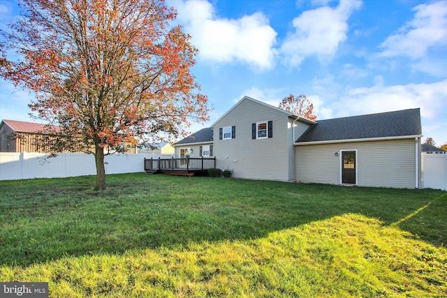 back of property with a yard and a deck