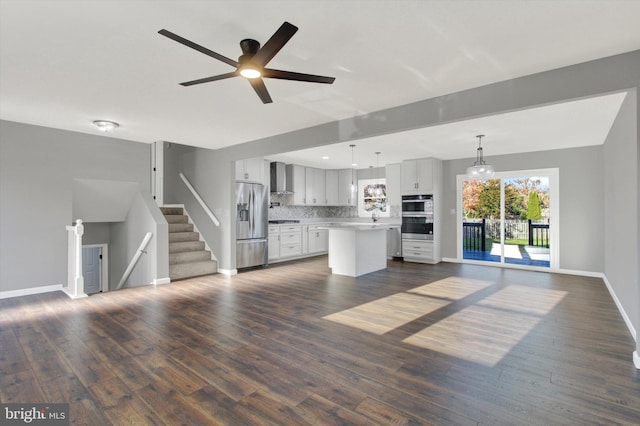 unfurnished living room featuring dark wood-type flooring and ceiling fan