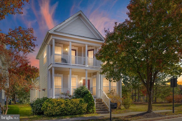 neoclassical / greek revival house featuring a balcony and covered porch