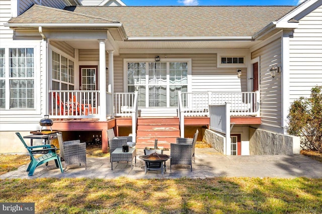 back of property with a wooden deck, a patio, and a fire pit