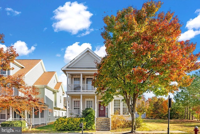 view of front of house with a porch, a balcony, and a front lawn