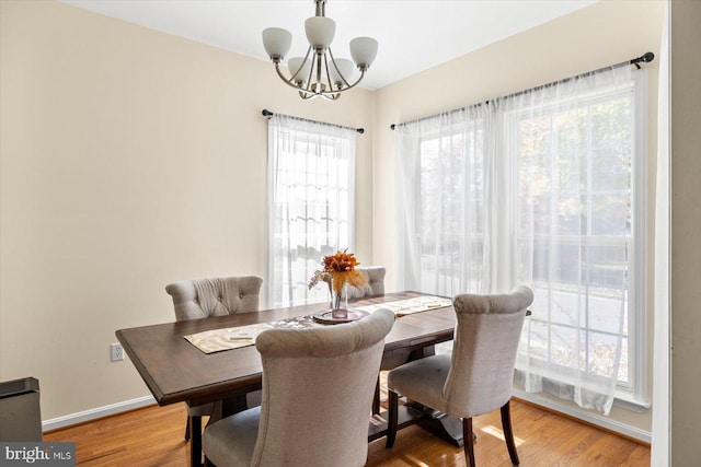 dining space with light hardwood / wood-style floors and a chandelier