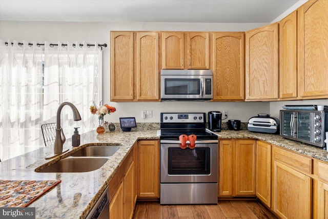 kitchen featuring light hardwood / wood-style floors, stainless steel appliances, light stone countertops, and sink