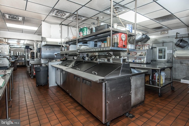 kitchen featuring dark tile patterned flooring and a drop ceiling