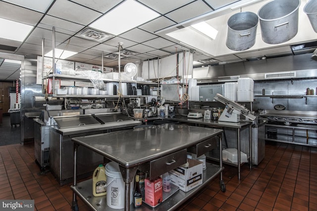 kitchen with dark tile patterned floors, a drop ceiling, and a center island