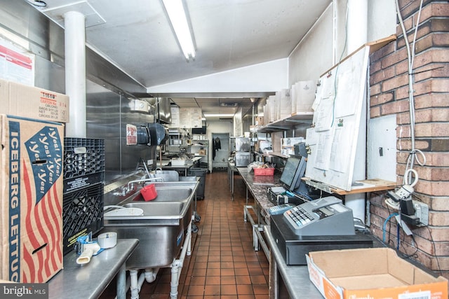 kitchen featuring lofted ceiling, dark tile patterned floors, and sink