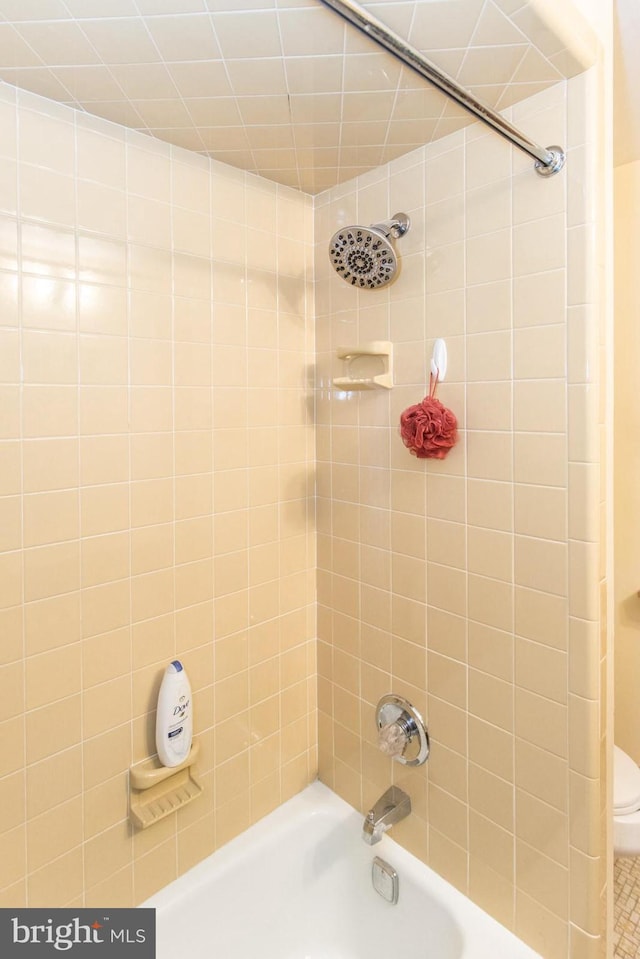 bathroom with toilet and tiled shower / bath combo