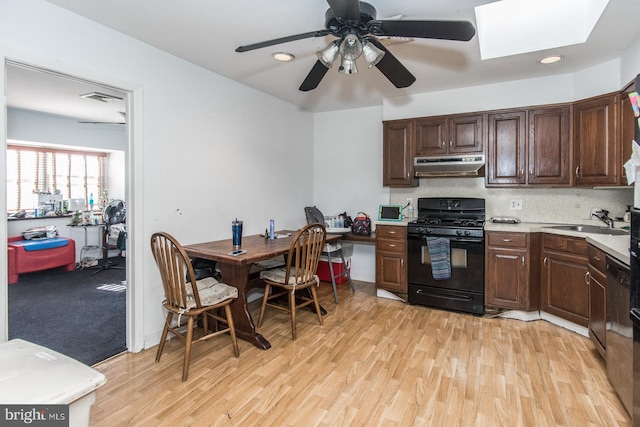 kitchen with black range with gas stovetop, a skylight, sink, light wood-type flooring, and ceiling fan