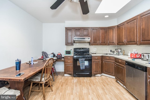 kitchen with backsplash, black gas stove, stainless steel dishwasher, a skylight, and light hardwood / wood-style floors