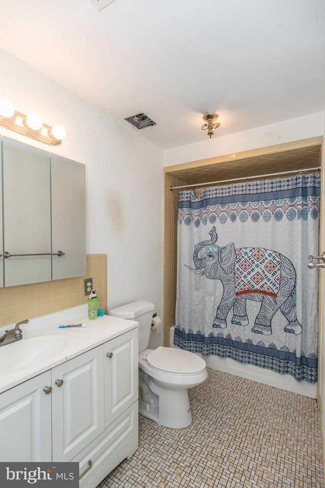 bathroom with vanity, decorative backsplash, toilet, and walk in shower