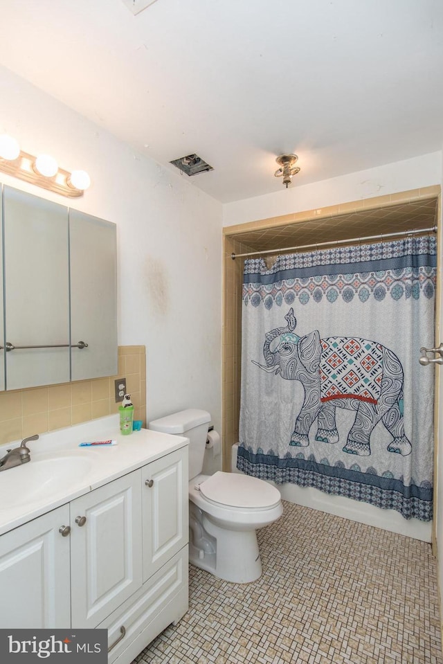 bathroom with toilet, vanity, visible vents, shower / bath combo, and backsplash
