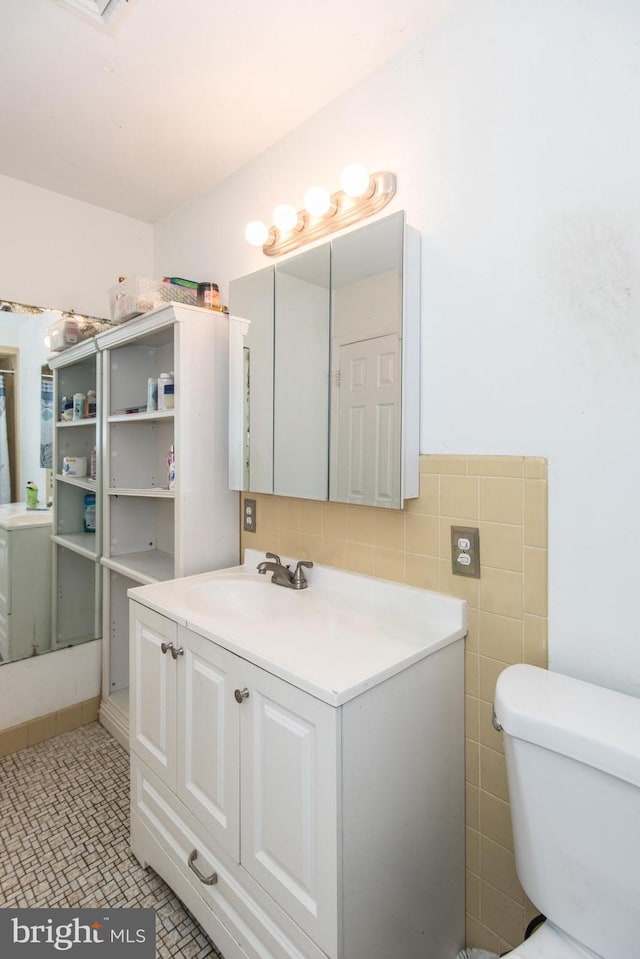 bathroom featuring toilet, vanity, tile walls, and tile patterned flooring