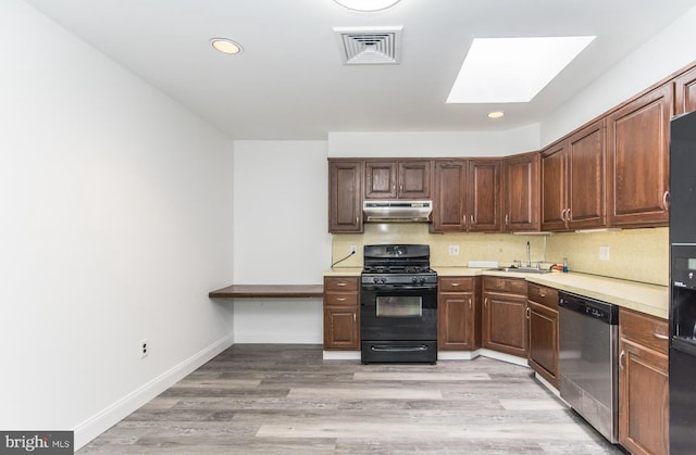 4624 Rhawn St, Philadelphia, PA 19136 - kitchen with black gas range oven, under cabinet range hood, dishwasher, a skylight, and a sink