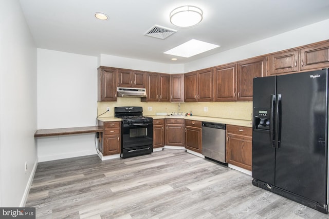 4624 Rhawn St, Philadelphia, PA 19136 - kitchen featuring black appliances, under cabinet range hood, a skylight, light countertops, and a sink