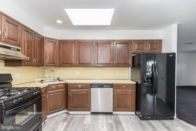 4624 Rhawn St, Philadelphia, PA 19136 - kitchen featuring black appliances, a skylight, a sink, under cabinet range hood, and light wood-style flooring