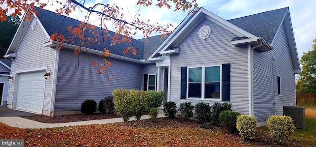 view of side of home with a garage and central air condition unit