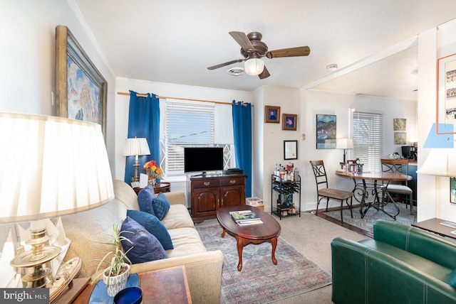 carpeted living room with crown molding and ceiling fan