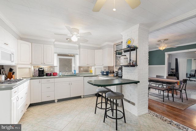 kitchen featuring white appliances, ornamental molding, sink, and white cabinets