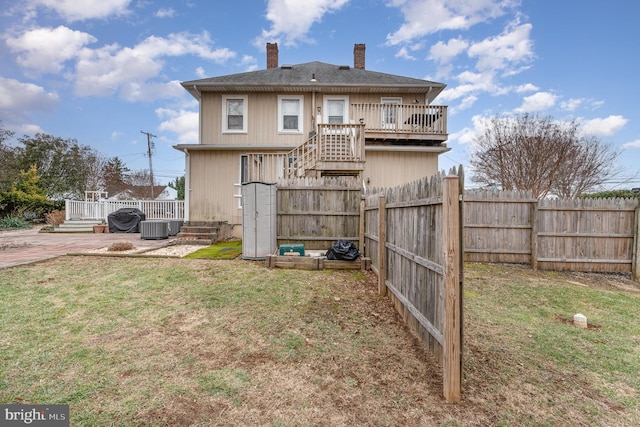 back of property with central AC, a deck, and a lawn