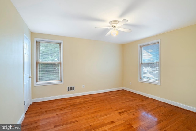 empty room featuring ceiling fan, a healthy amount of sunlight, and light hardwood / wood-style flooring