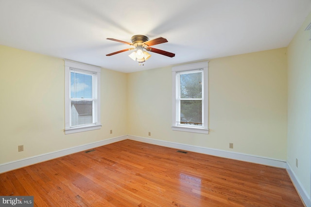 unfurnished room with a wealth of natural light, ceiling fan, and light hardwood / wood-style floors