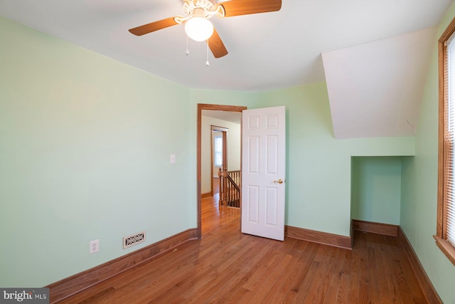 unfurnished bedroom with ceiling fan, light wood-type flooring, and multiple windows