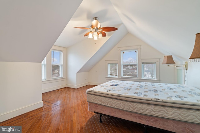 bedroom featuring ceiling fan, light hardwood / wood-style floors, vaulted ceiling, and multiple windows