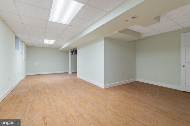 basement featuring a drop ceiling and light wood-type flooring