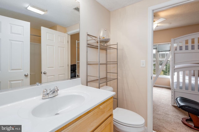 bathroom featuring vanity, ceiling fan, toilet, and a textured ceiling