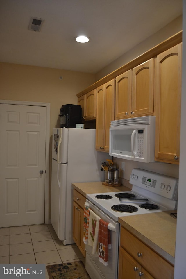 kitchen featuring light tile patterned flooring, white appliances, and light brown cabinetry