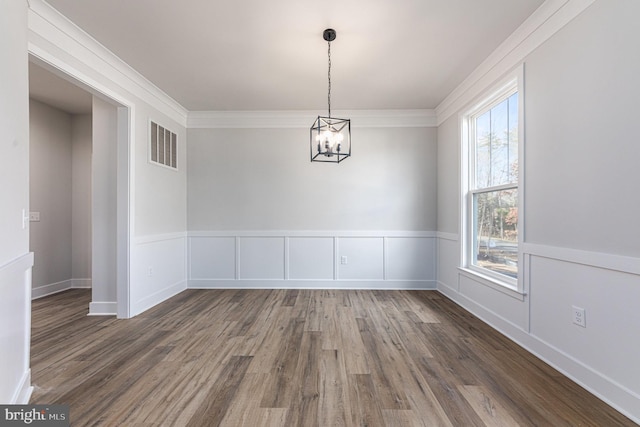 unfurnished dining area featuring a chandelier, crown molding, and dark hardwood / wood-style flooring