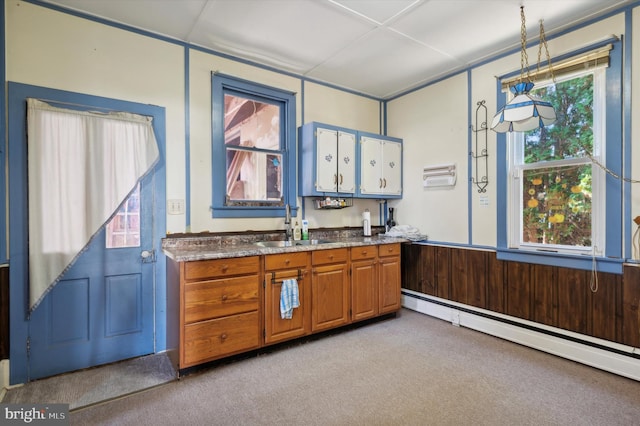 kitchen with sink, a baseboard heating unit, light carpet, and wooden walls