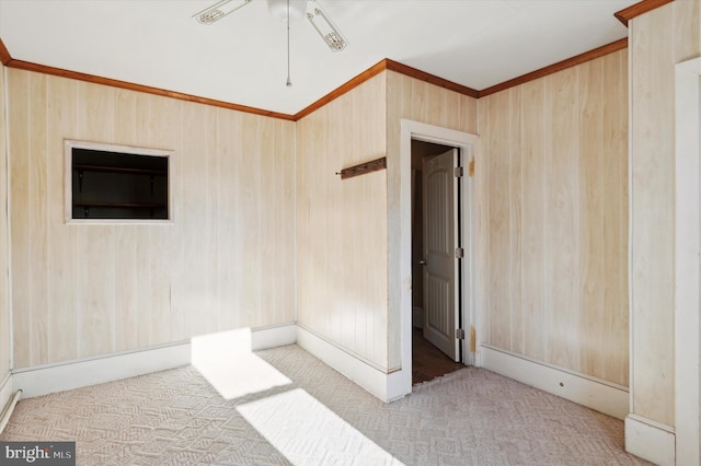 spare room with light carpet, crown molding, and wood walls