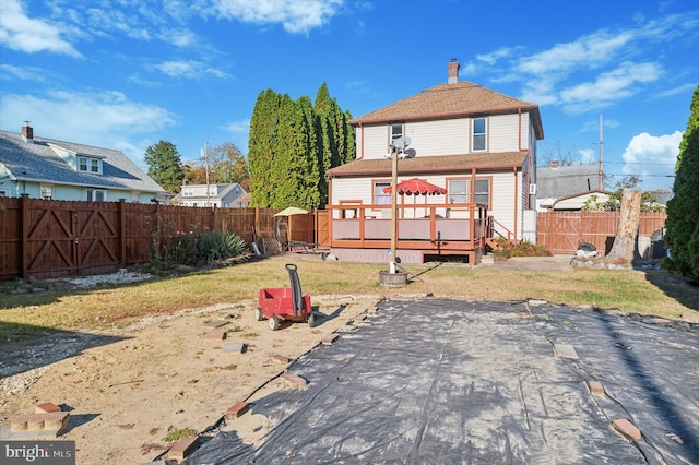 rear view of property with a patio area, a wooden deck, and a lawn