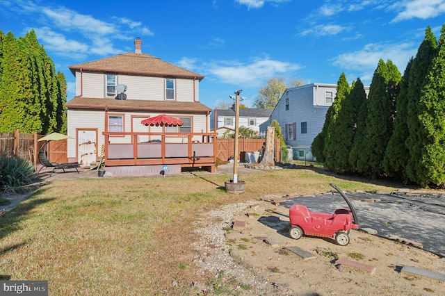 back of property with a deck and a lawn