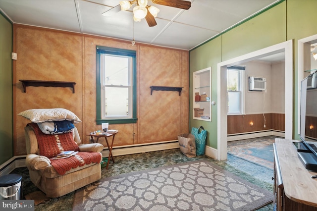 sitting room with an AC wall unit, a baseboard radiator, wooden walls, and ceiling fan