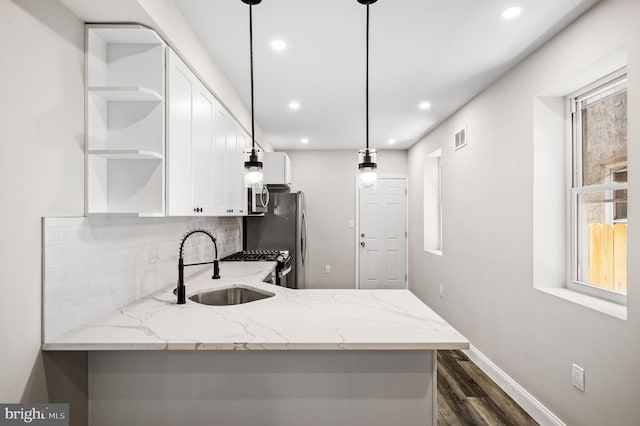 kitchen featuring light stone countertops, white cabinets, kitchen peninsula, and pendant lighting