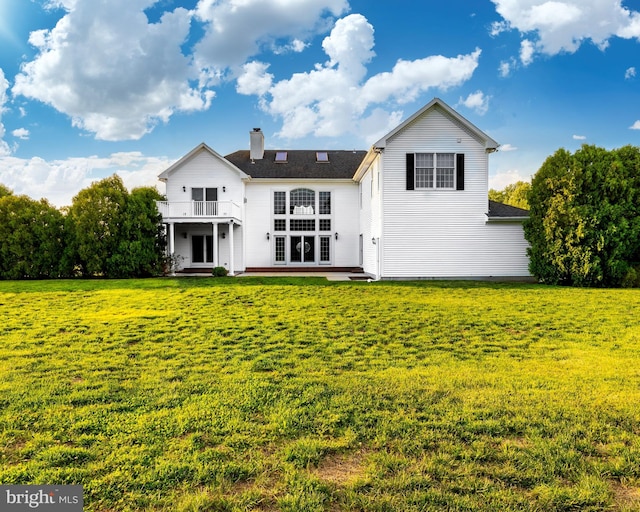 back of property with a lawn, a patio, and a balcony