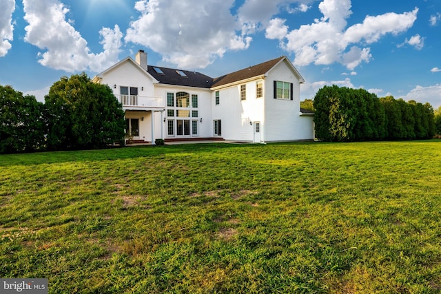 rear view of property featuring a balcony, a patio, and a yard