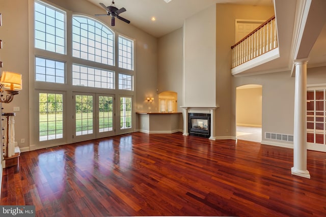 unfurnished living room featuring a towering ceiling, a tiled fireplace, crown molding, and hardwood / wood-style flooring