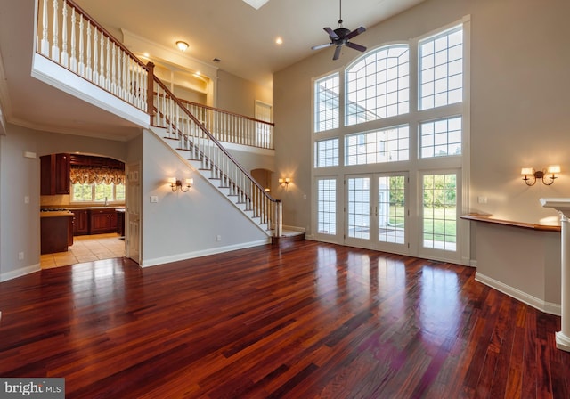 unfurnished living room with a towering ceiling, wood-type flooring, and a healthy amount of sunlight