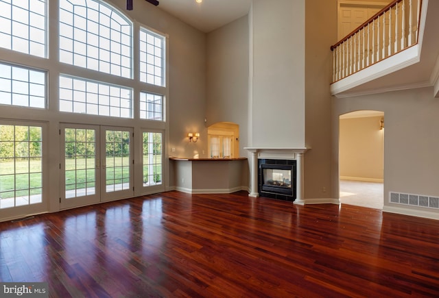 unfurnished living room featuring a multi sided fireplace, a high ceiling, wood-type flooring, and ceiling fan