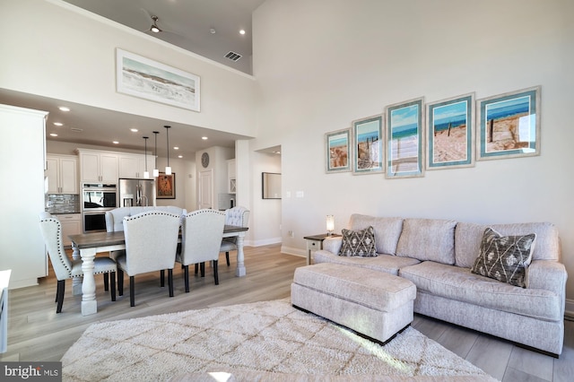 living room with light wood-type flooring and a high ceiling