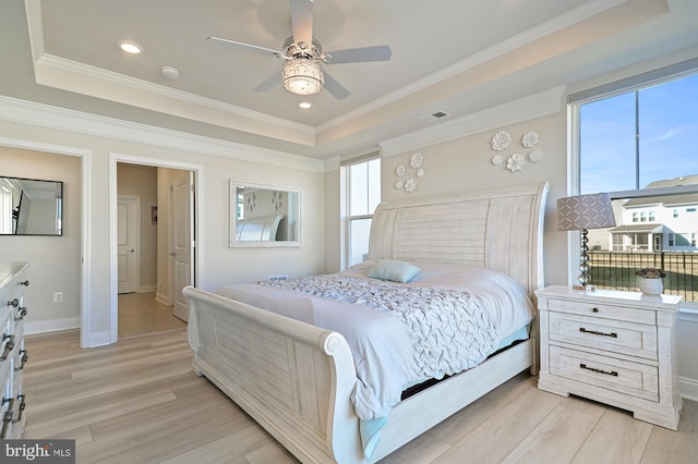 bedroom with ornamental molding, a tray ceiling, ceiling fan, and light hardwood / wood-style flooring