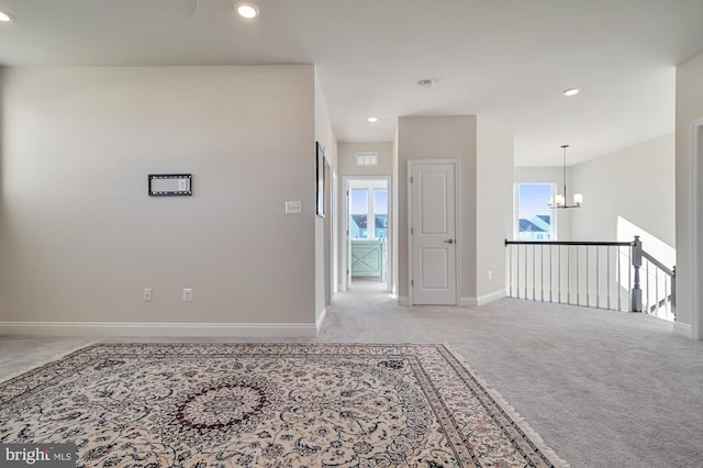 carpeted spare room featuring a notable chandelier