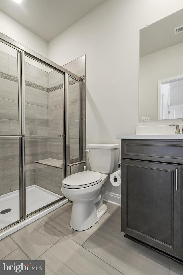 bathroom featuring vanity, toilet, and a shower with shower door