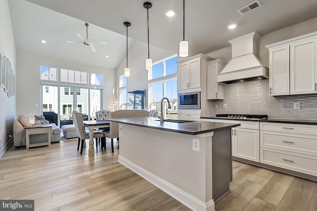 kitchen featuring white cabinets, high vaulted ceiling, light hardwood / wood-style flooring, and custom exhaust hood